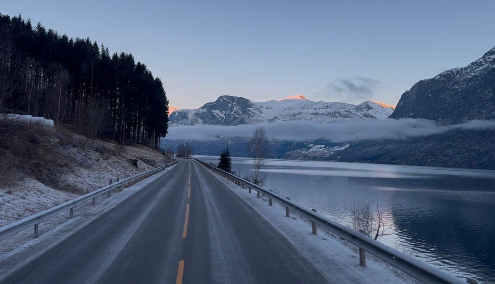 Norská silnice podél fjordu za soumraku